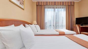 Quarto de hotel com uma cama grande, televisão e janela com cortinas.