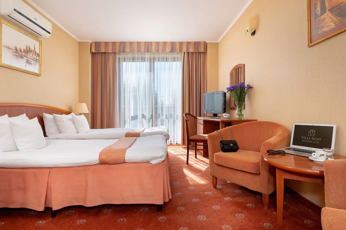 A hotel room with two beds, a desk with a computer, a chair, and a TV.