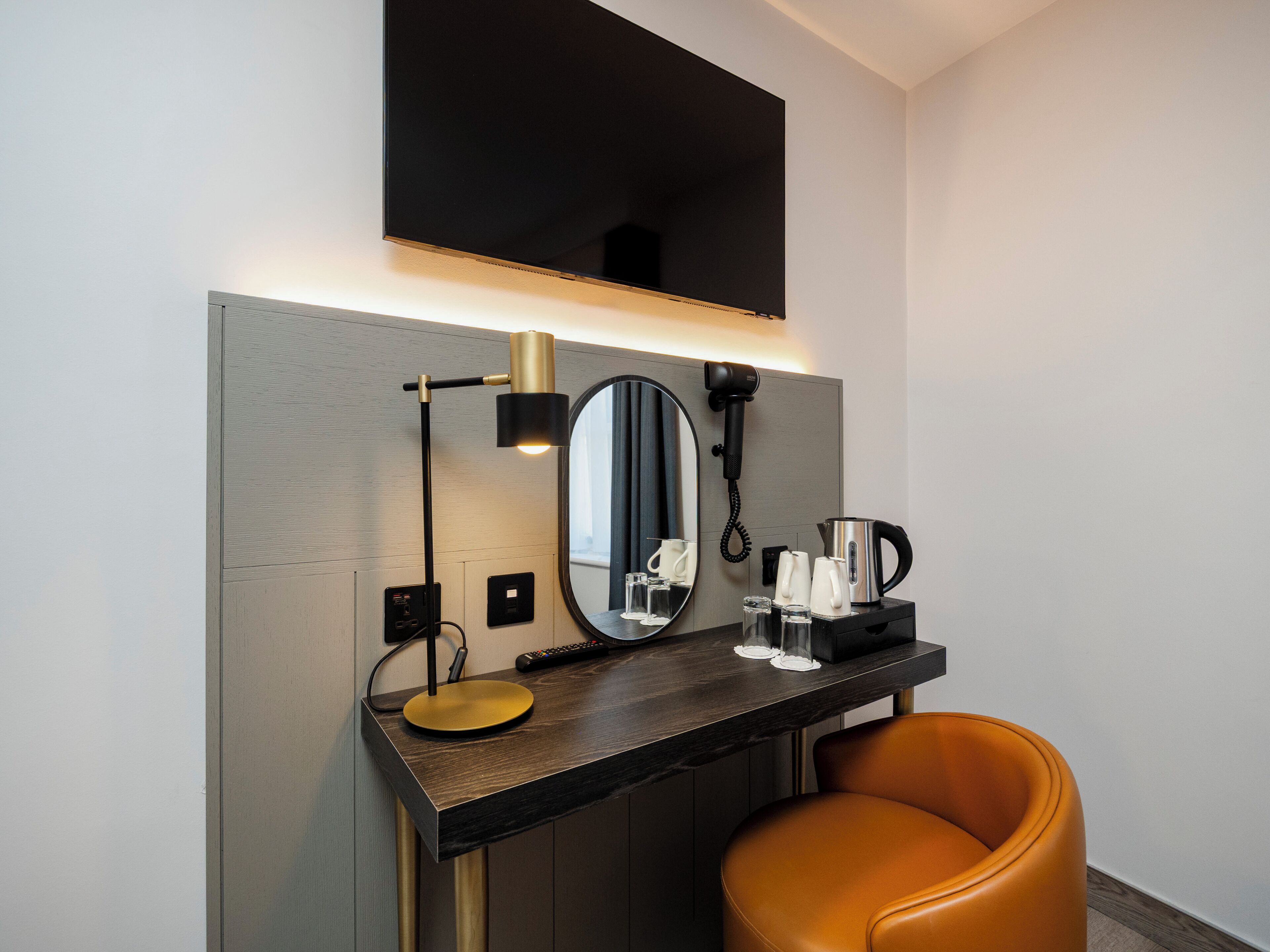 Une salle de bain moderne équipée d’un meuble-lavabo, d’un miroir, d’un sèche-cheveux et d’une machine à café.