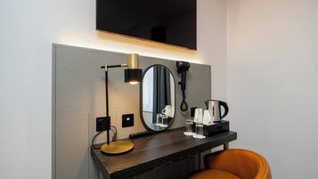Een moderne badkamer met een wastafel, spiegel, haardroger en een koffiezetapparaat.
