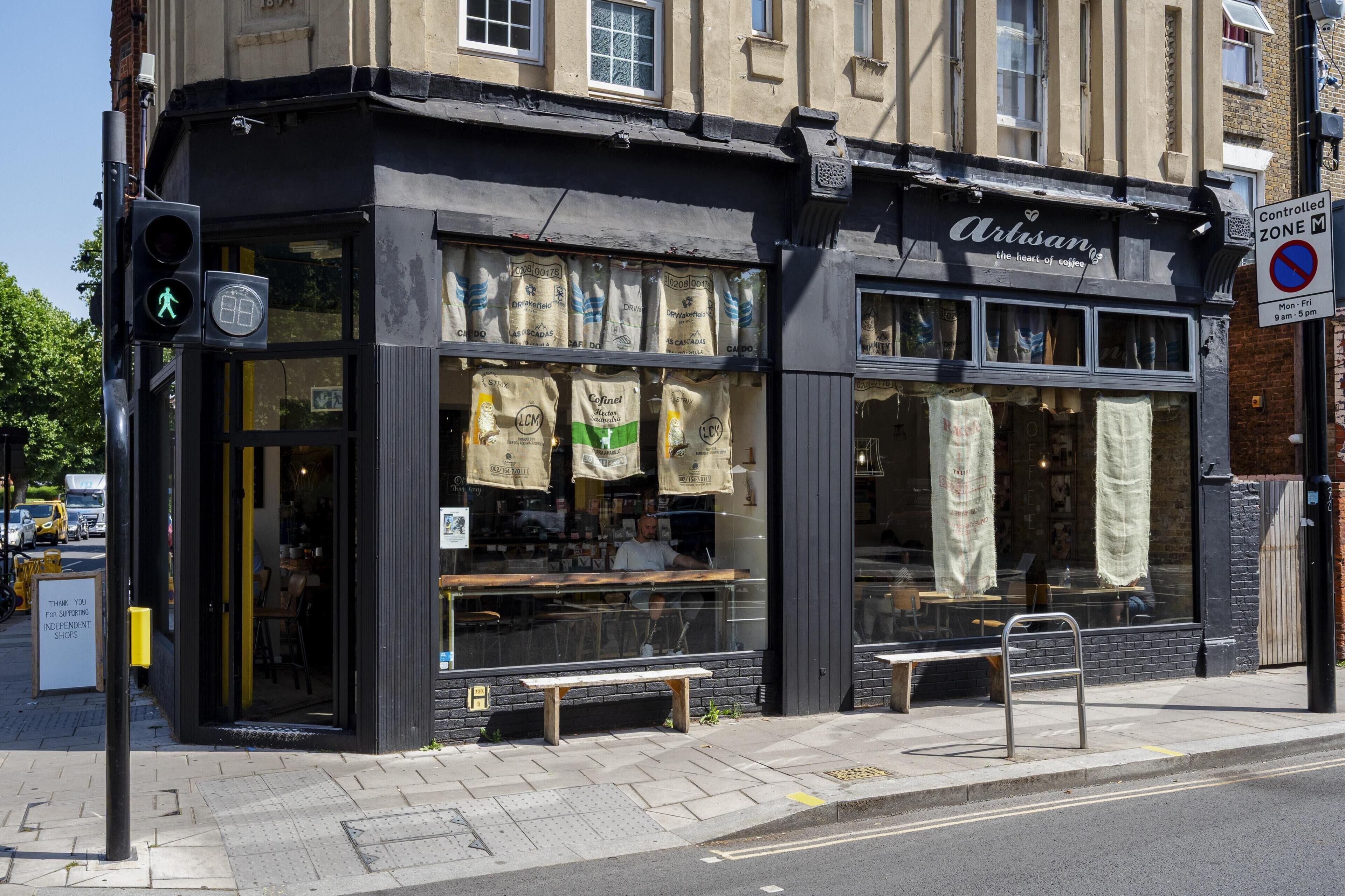 A storefront with a black facade, large display windows, and a bench outside.