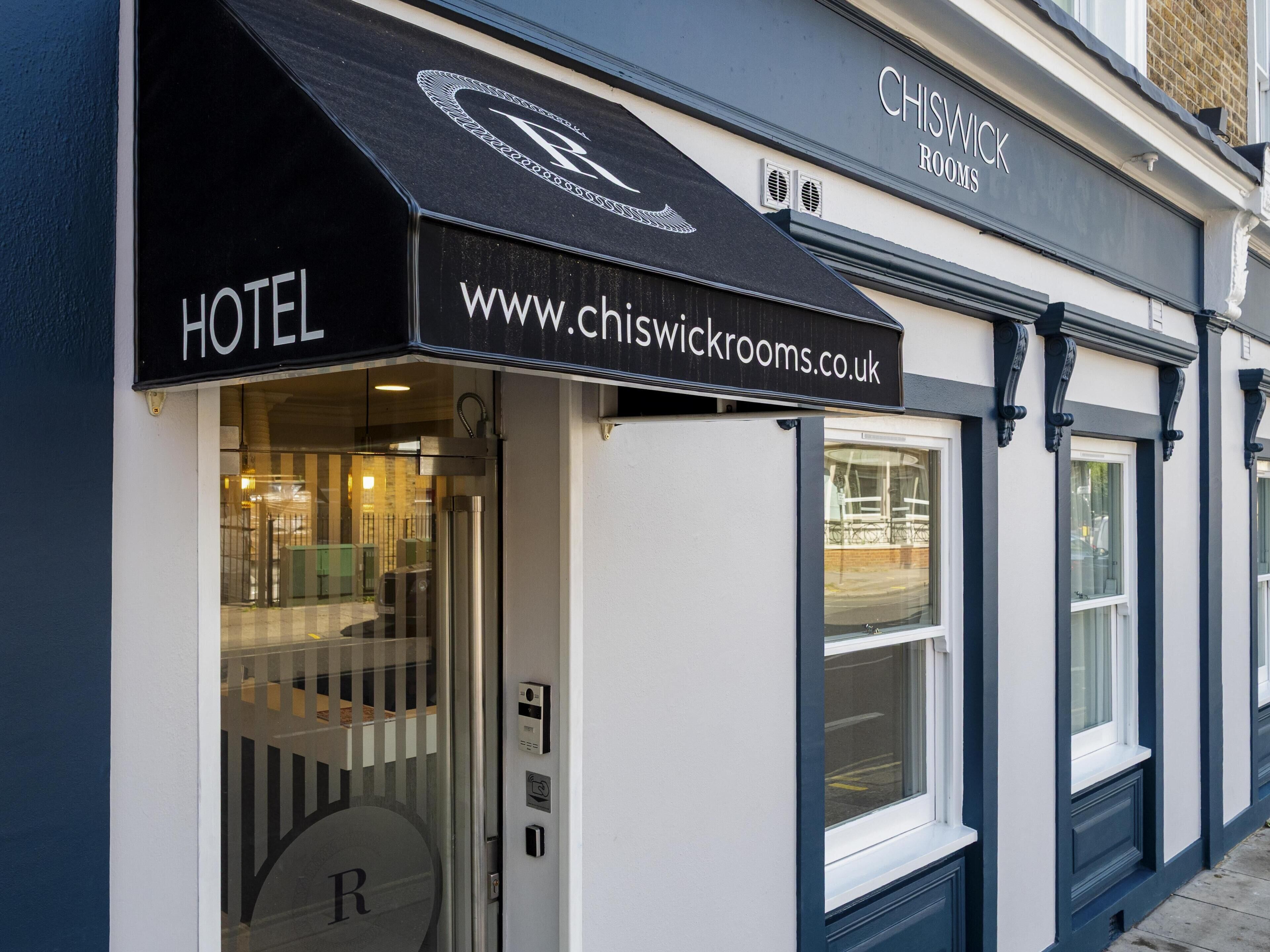 A hotel entrance with a black awning displaying the name 'CHISWICK ROOMS' and the website 'www.chiswickrooms.co.uk'.