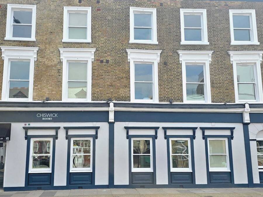 A two-story building with a ground-floor shop named 'CHISWICK ROOMS' and a hotel sign above it.