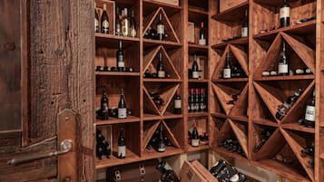 A wine cellar with wooden shelves and racks holding various wine bottles.