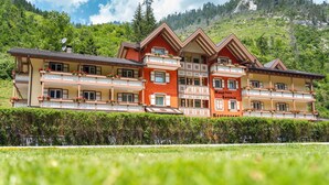 Un hôtel à plusieurs étages doté de balcons, situé dans une région montagneuse à la végétation luxuriante.
