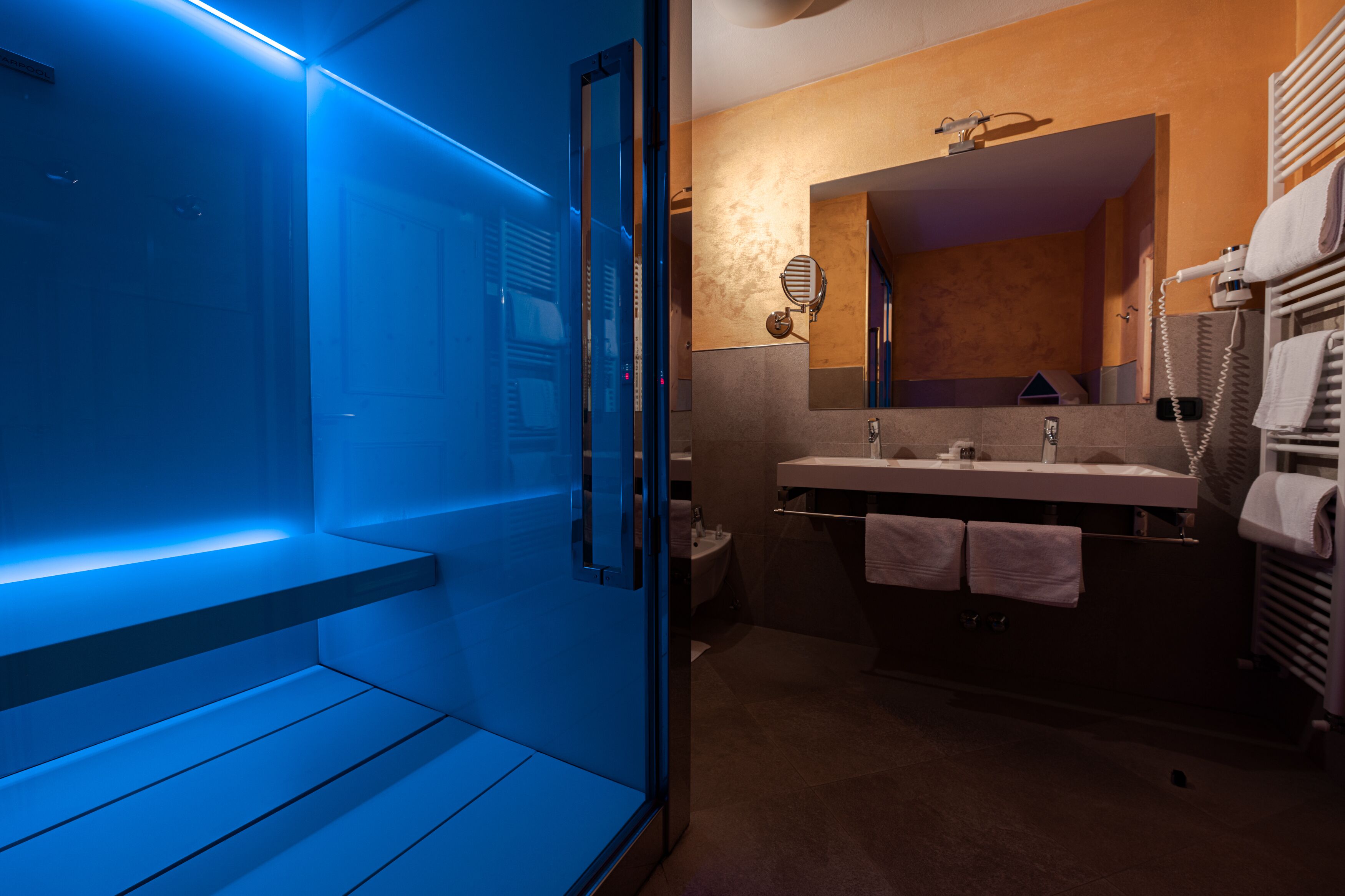 A modern bathroom with a glass shower enclosure, a vanity with a mirror, and a towel rack.