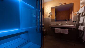 Une salle de bain moderne avec une douche à parois de verre, un meuble-lavabo avec un miroir et un porte-serviettes.