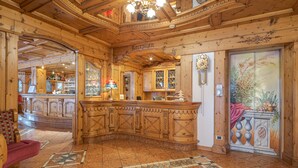 Un espace d’accueil doté d’un comptoir de réception en bois, d’un lustre et d’un sol carrelé orné d’un motif géométrique.
