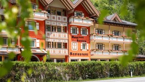 Un hôtel à plusieurs étages, de style architectural traditionnel, doté de balcons ornés de jardinières et d’une enseigne indiquant qu’il abrite un restaurant.