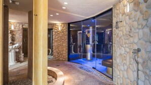 Une salle de bain aux murs en pierre, dotée d’un sol en pierre, d’une cabine de douche en verre et d’un sol recouvert de carreaux de marbre.
