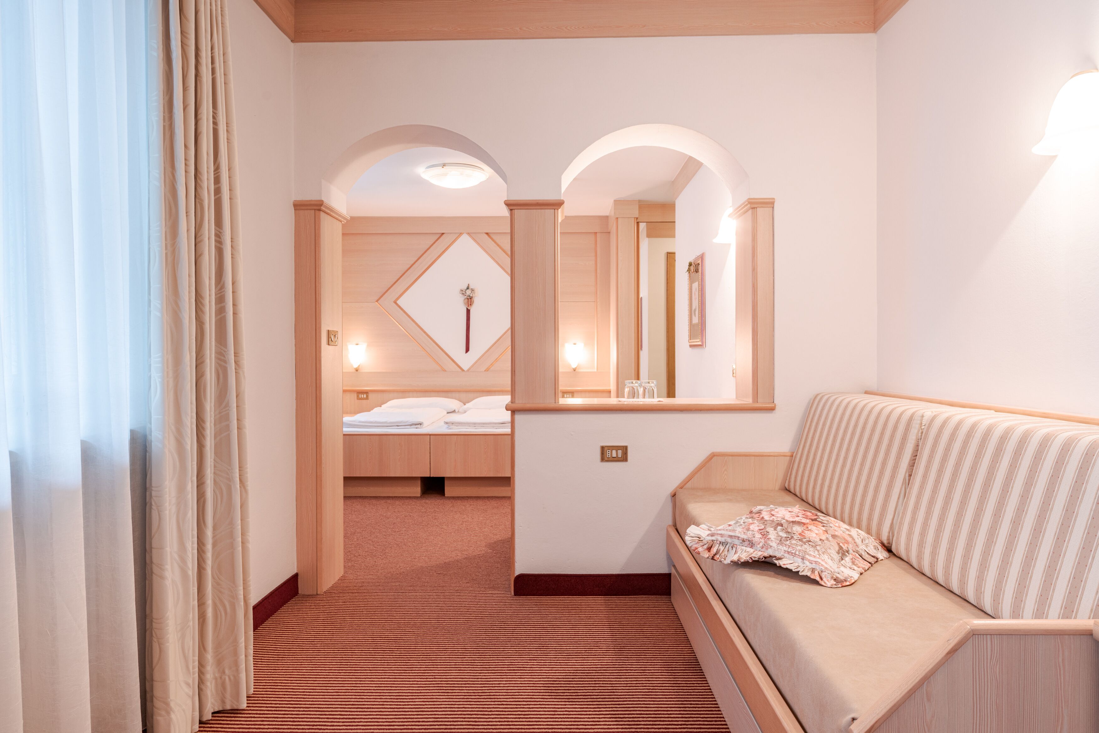 Une chambre d’hôtel avec un lit, un canapé, un miroir et une petite table.
