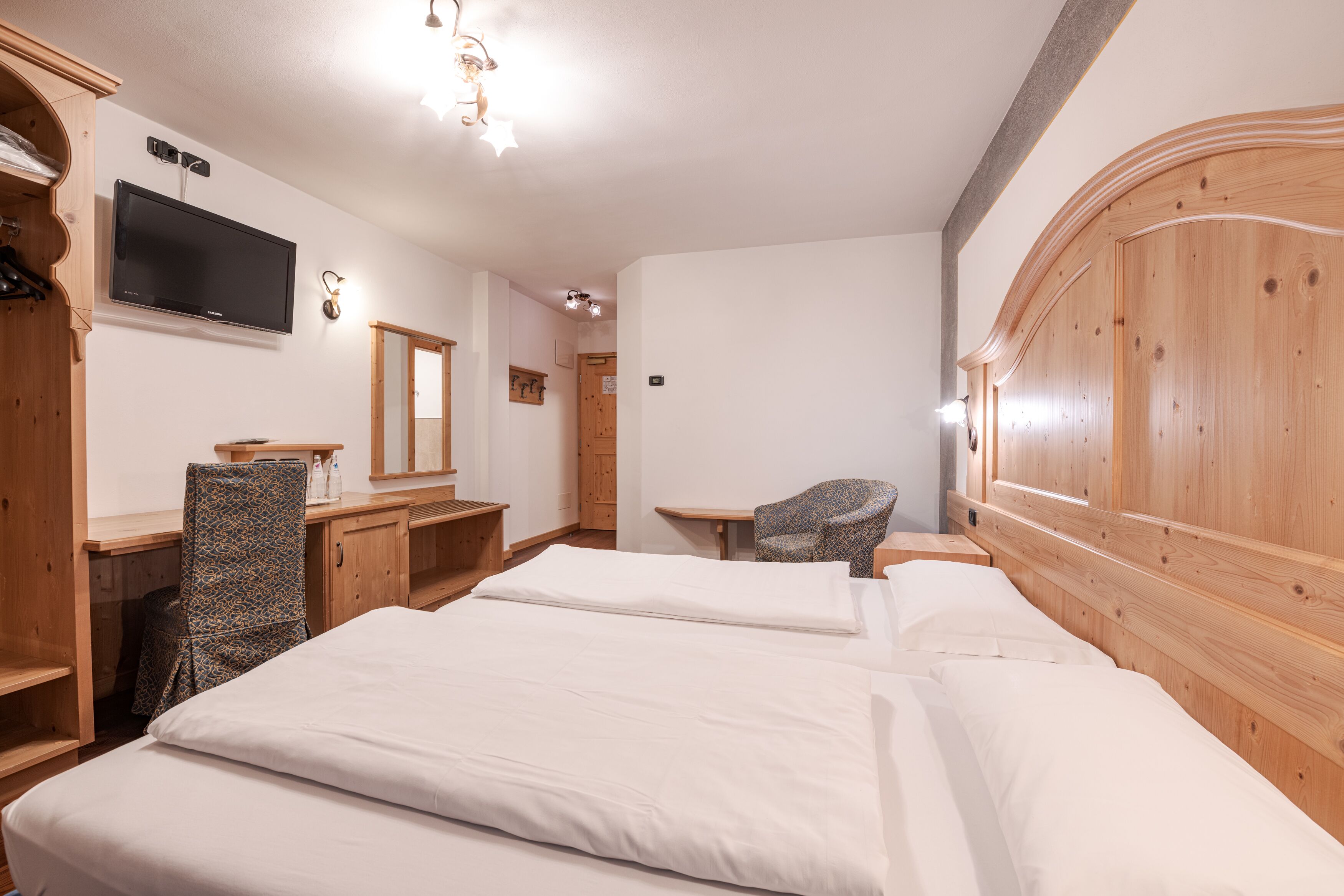 Hotellihuone, jossa on kaksi sänkyä, televisio, työpöytä ja tuoli.