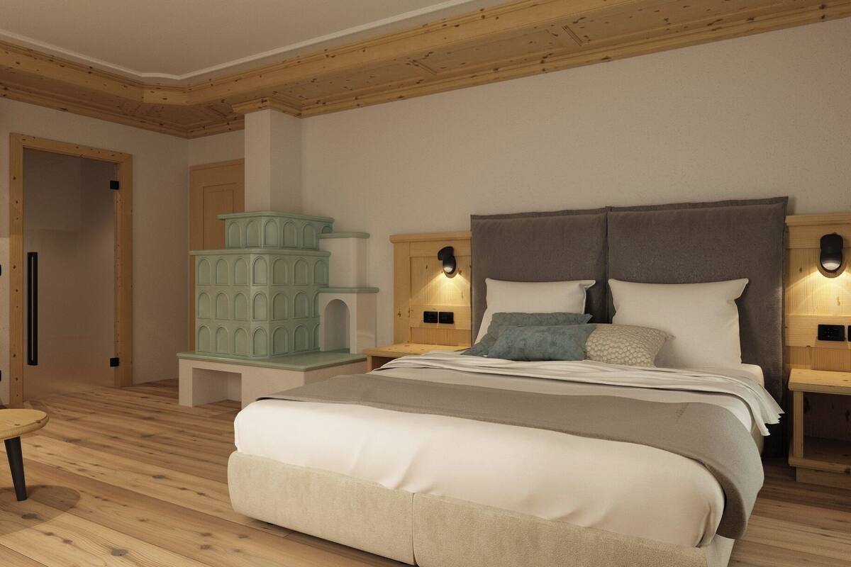 A bedroom with a large bed, wooden headboard, bedside tables with lamps, and a small seating area.