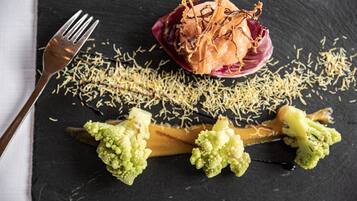 A slate serving board with a dish of food, including broccoli and a red sauce, and a fork on the left.