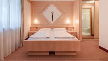 Een hotelkamer met een groot bed, een houten hoofdbord, twee nachtkastjes, een spiegel en een rode vloerbedekking.