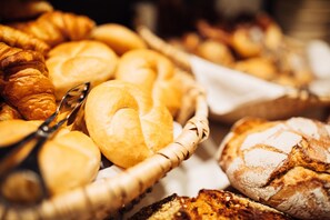 Una cesta llena de panes variados, incluyendo croissants y barras.