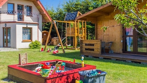Une cabane en bois avec une balançoire et un espace de jeux.