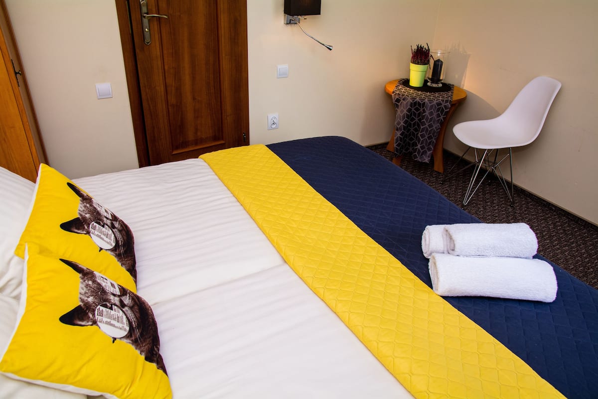 Una habitación de hotel con cama, una mesita con silla y televisión instalada en la pared.