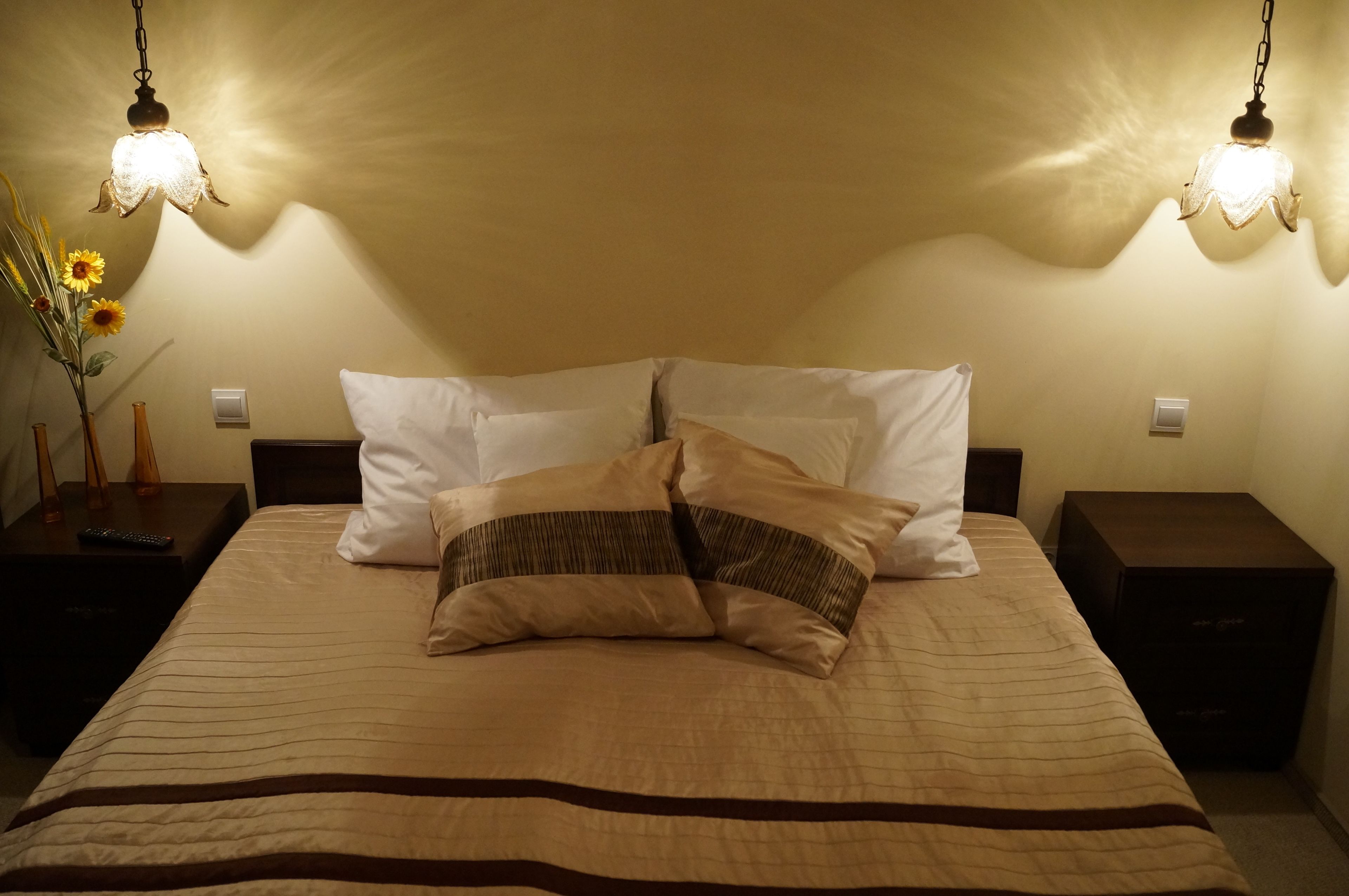 Un lit bien fait, recouvert d’une couvre-lit à rayures et agrémenté de deux oreillers, avec deux tables de chevet de chaque côté, sur lesquelles sont posées des lampes.