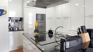 A modern kitchen with white cabinets, a built-in oven, a microwave, and a stainless steel range hood. - Lisbon Rentals Chiado (Lisbon)