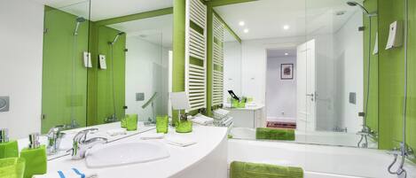 Ein modernes Badezimmer mit einem großen Spiegel, einem weißen Waschbecken und einer Badewanne.