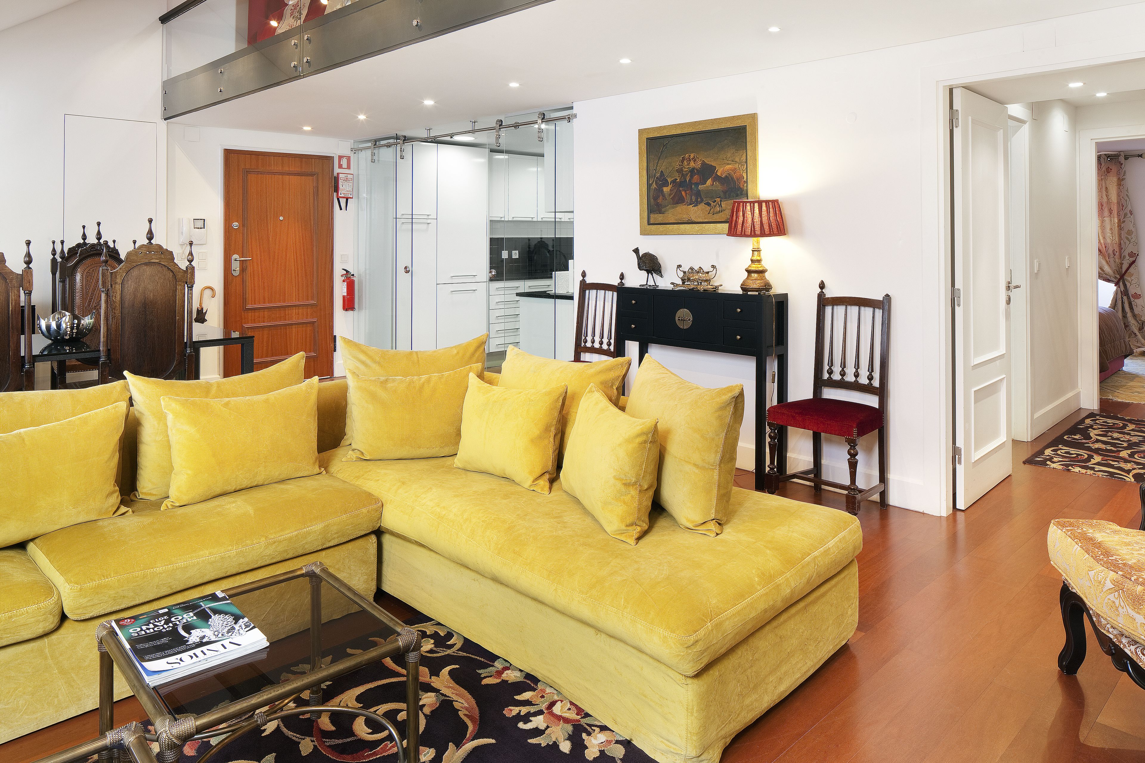 Una sala de estar con un sofá amarillo, una mesa de centro de vidrio y una chimenea.