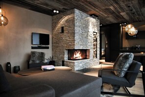A modern living room with a stone fireplace, a flat-screen TV, and contemporary furniture. - Hotel Zhero - Ischgl/Kappl (Kappl)