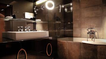 A modern bathroom with a large mirror, a double sink, a bathtub, and a glass shower enclosure.