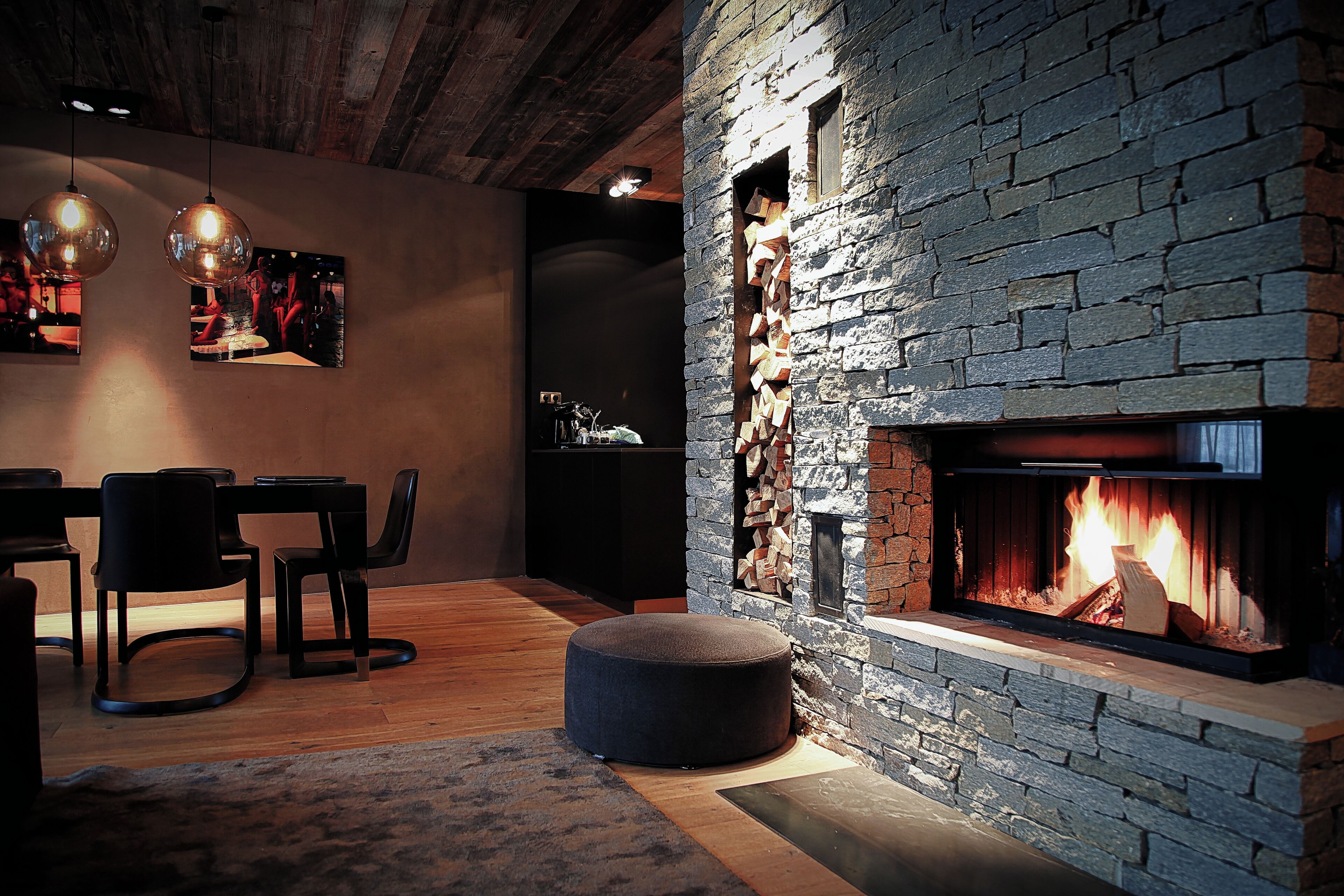 Un salon chaleureux avec une cheminée en pierre, un plancher en bois et des meubles modernes.