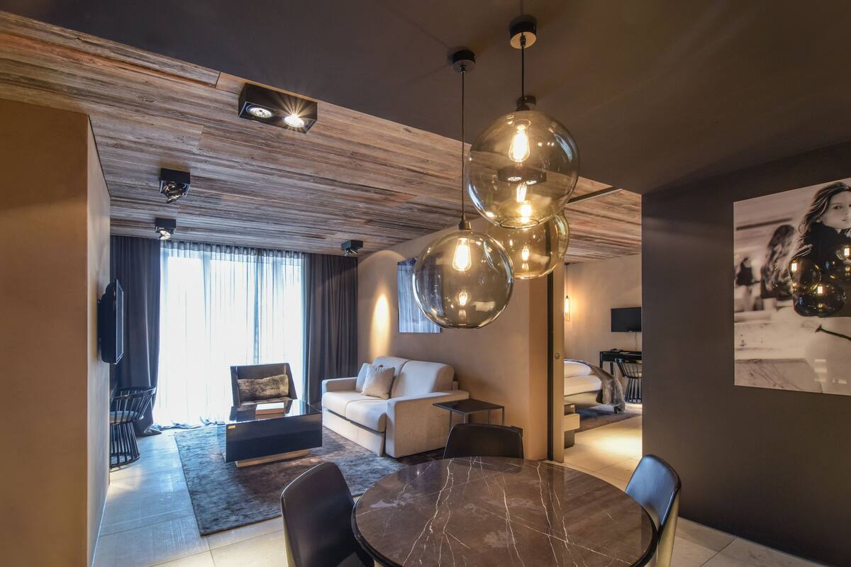 A modern living room with a marble dining table, a sofa, and a large pendant light.