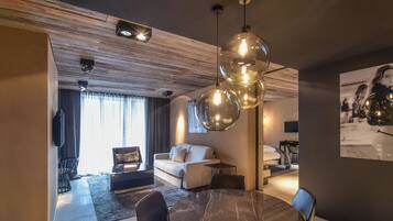 A modern living room with a marble dining table, a sofa, and a large pendant light.