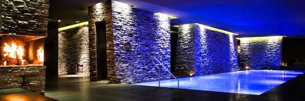 A stone-walled room with a fire feature and a blue-lit pool area. - Hotel Zhero - Ischgl/Kappl (Kappl)