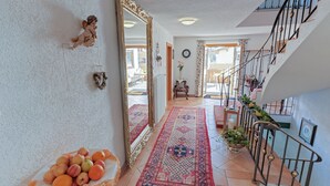 A spacious hallway with a large mirror, a staircase with a railing, and a fruit bowl on the floor. - Haus Schrofenstein (Lech am Arlberg)