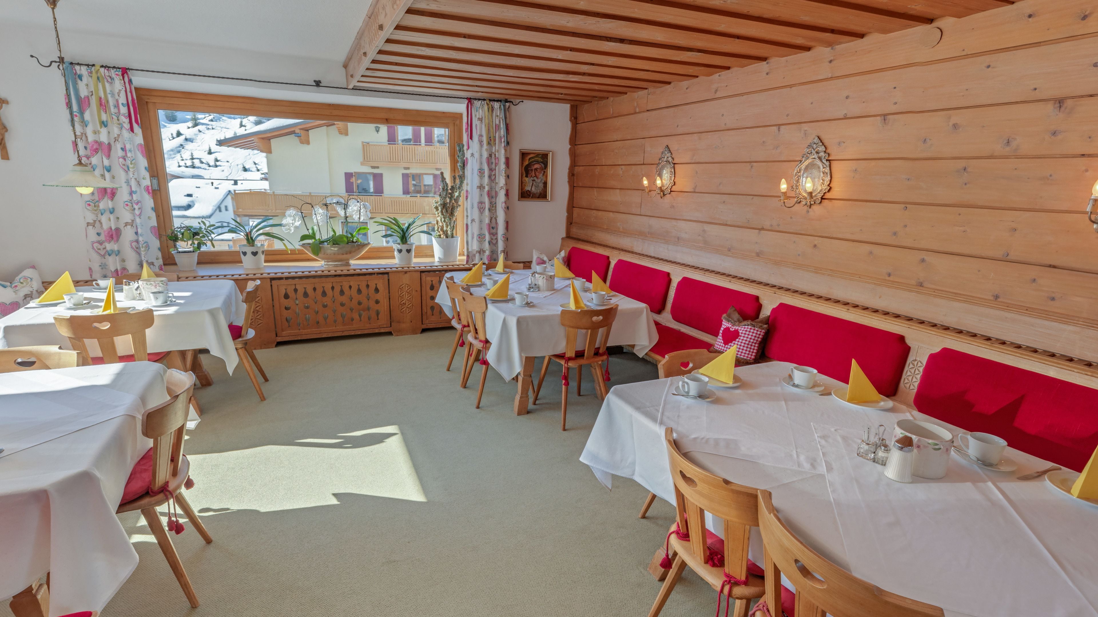 Un restaurante con varias mesas, sillas de madera y bancos acolchados rojos.