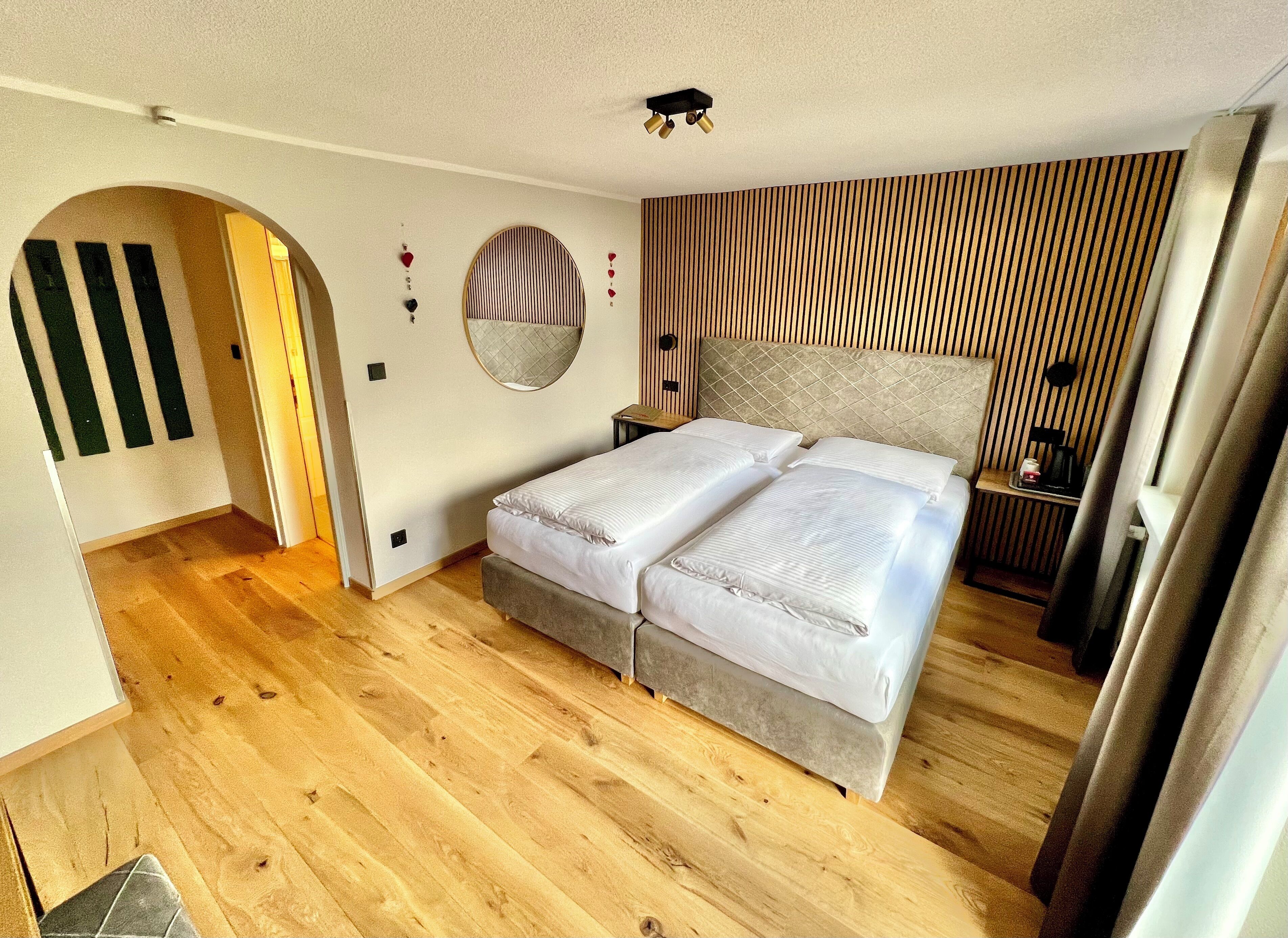 Una camera da letto con un letto, un comodino, uno specchio e un pannello parete in legno.