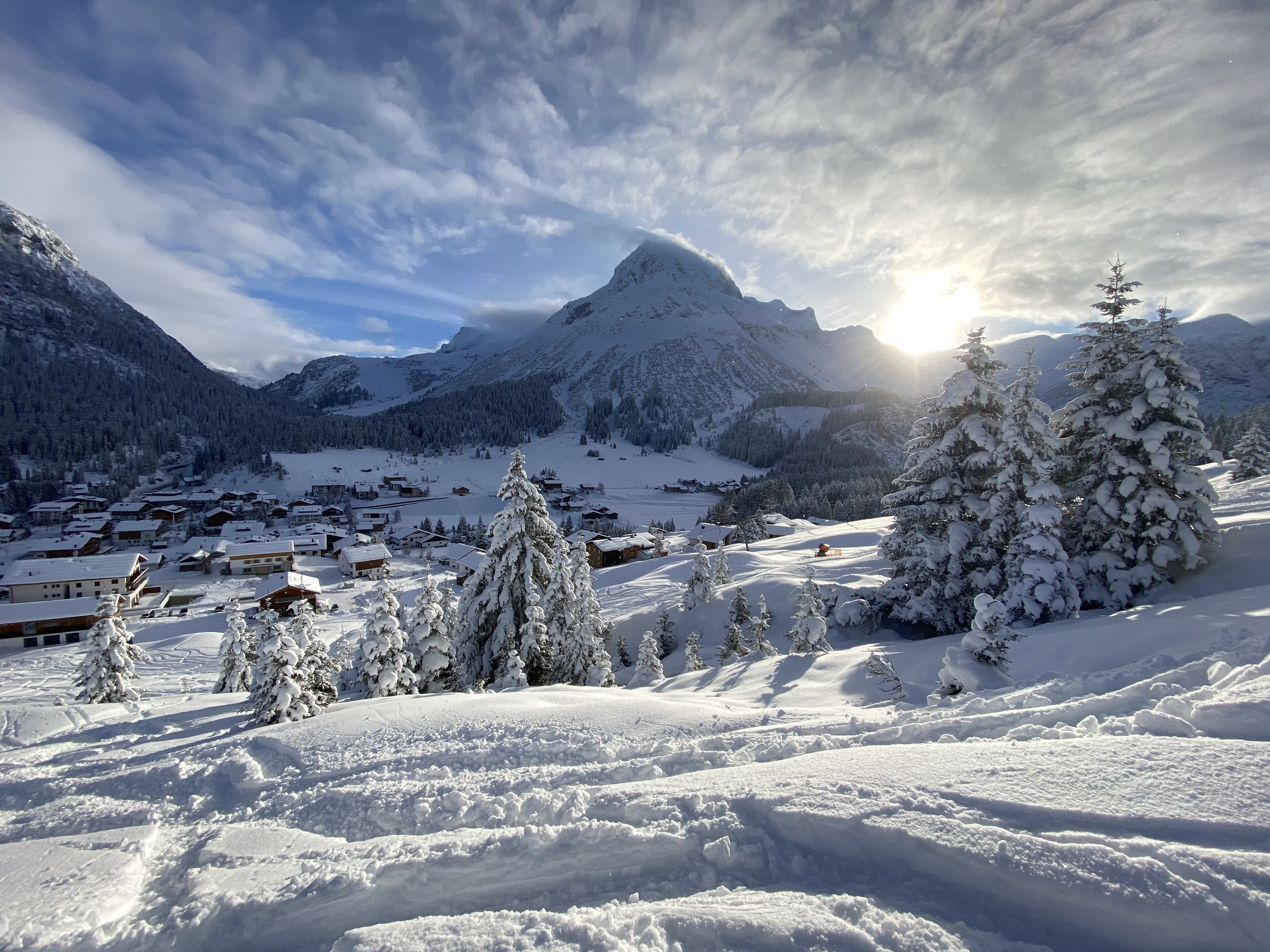 A snow-covered mountain village with traditional wooden houses and snow-laden trees.