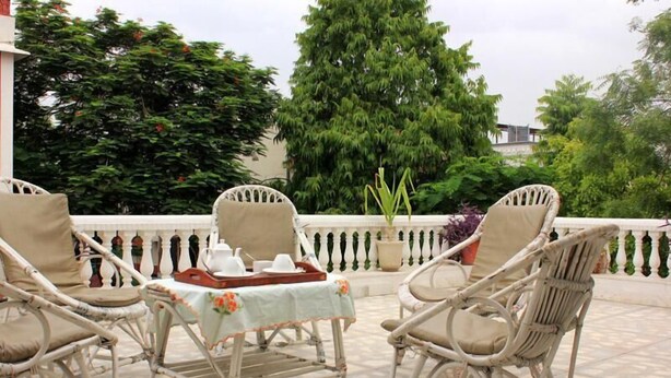 Una terraza con muebles de mimbre y una mesa lista para dos personas, rodeada de exuberante follaje.