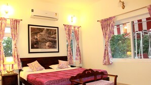 Un dormitorio con cama de madera, una mesita de noche, un banco, aire acondicionado instalado en la pared y una ventana con cortinas.