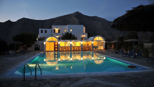 Una piscina al aire libre, sombrillas, sillones reclinables de piscina