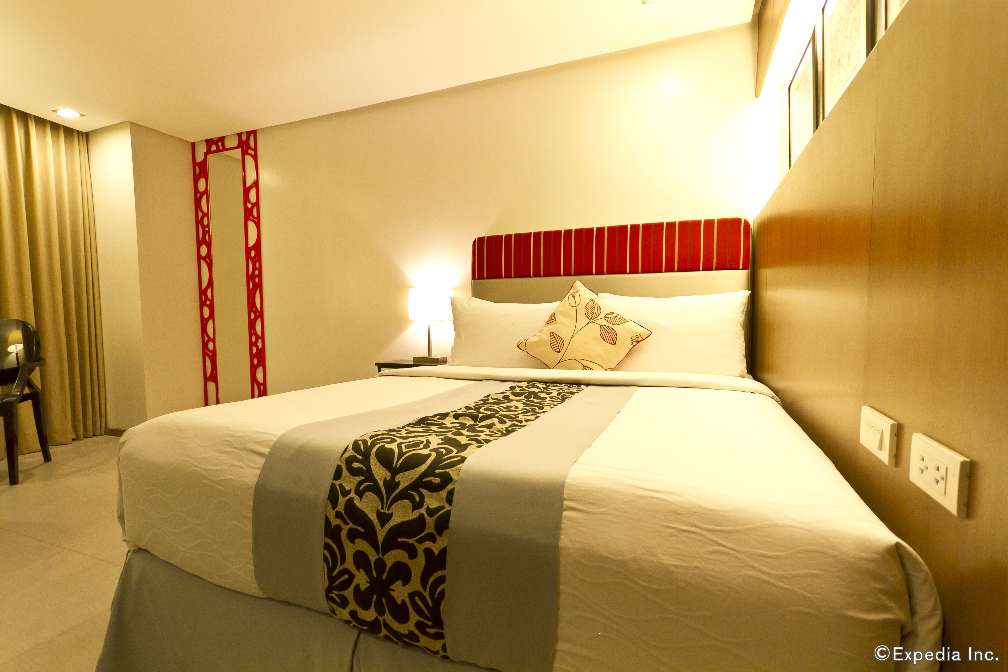 A hotel room with a large bed, a bedside table, a lamp, and a chair.
