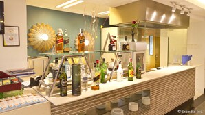 Un espace bar avec différentes bouteilles d’alcool, une vitrine et un élément décoratif mural.
