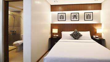 Una habitación de hotel con una cama grande, dos lámparas de noche, un cabecero de madera y tres cuadros enmarcados en la pared.