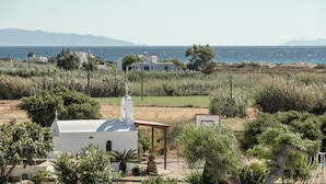 Una propiedad costera con un edificio blanco, una pérgola y vistas al mar y a las montañas.