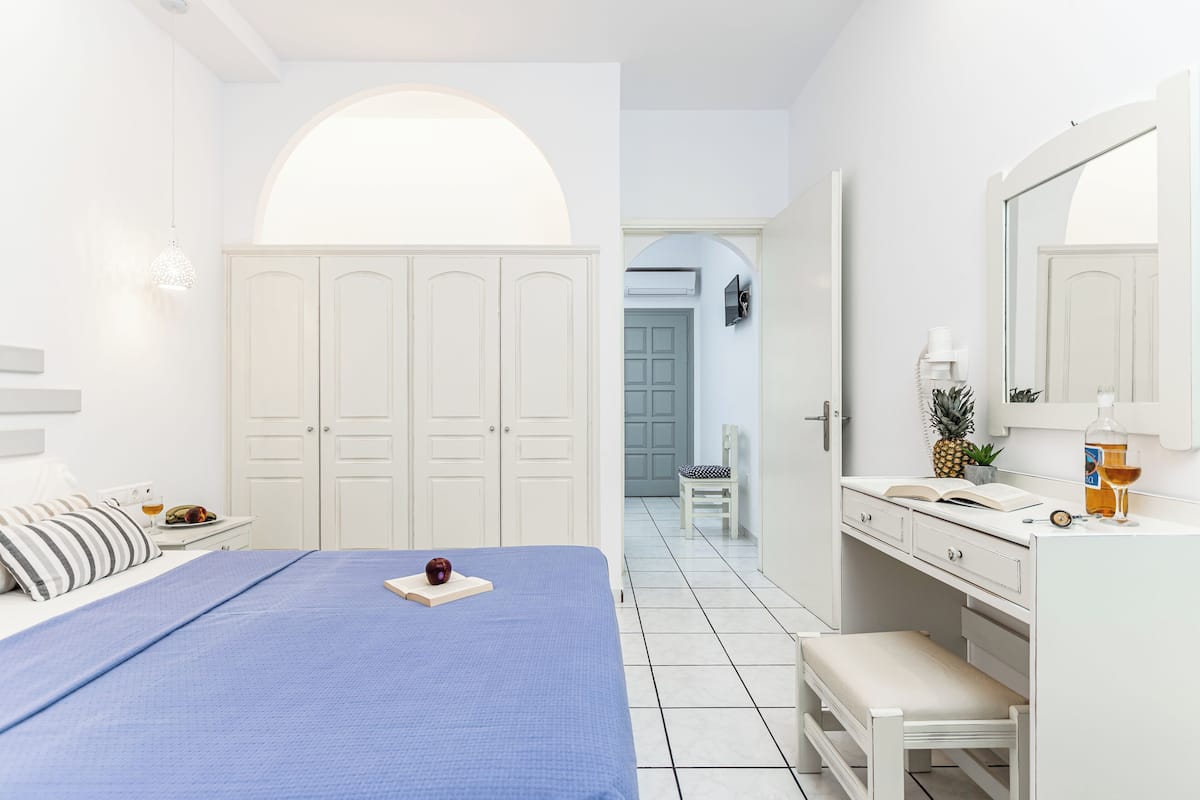A bedroom with a bed, a dresser, a mirror, and a door leading to another room.