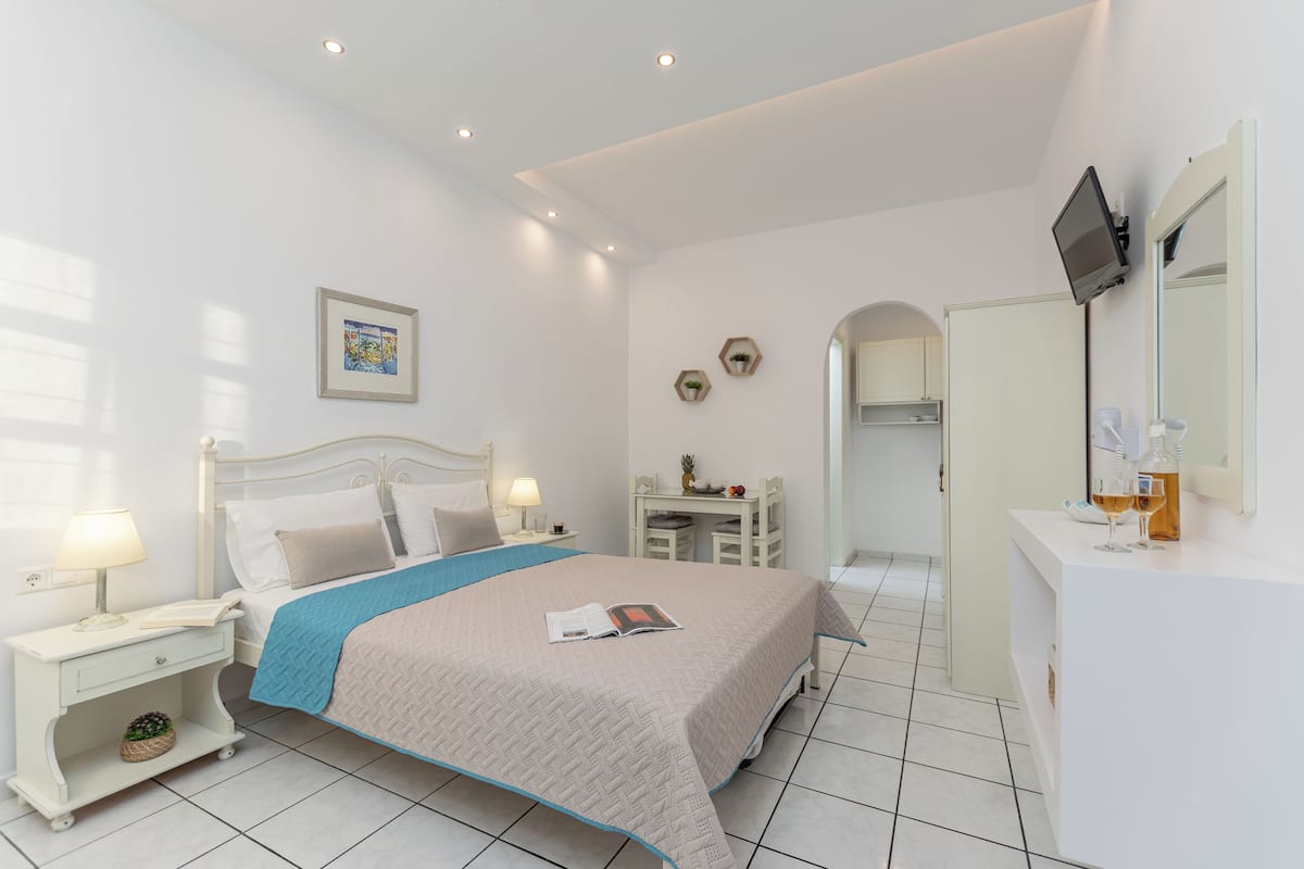 A bedroom with a bed, bedside tables, a desk, a TV, and a mirror.
