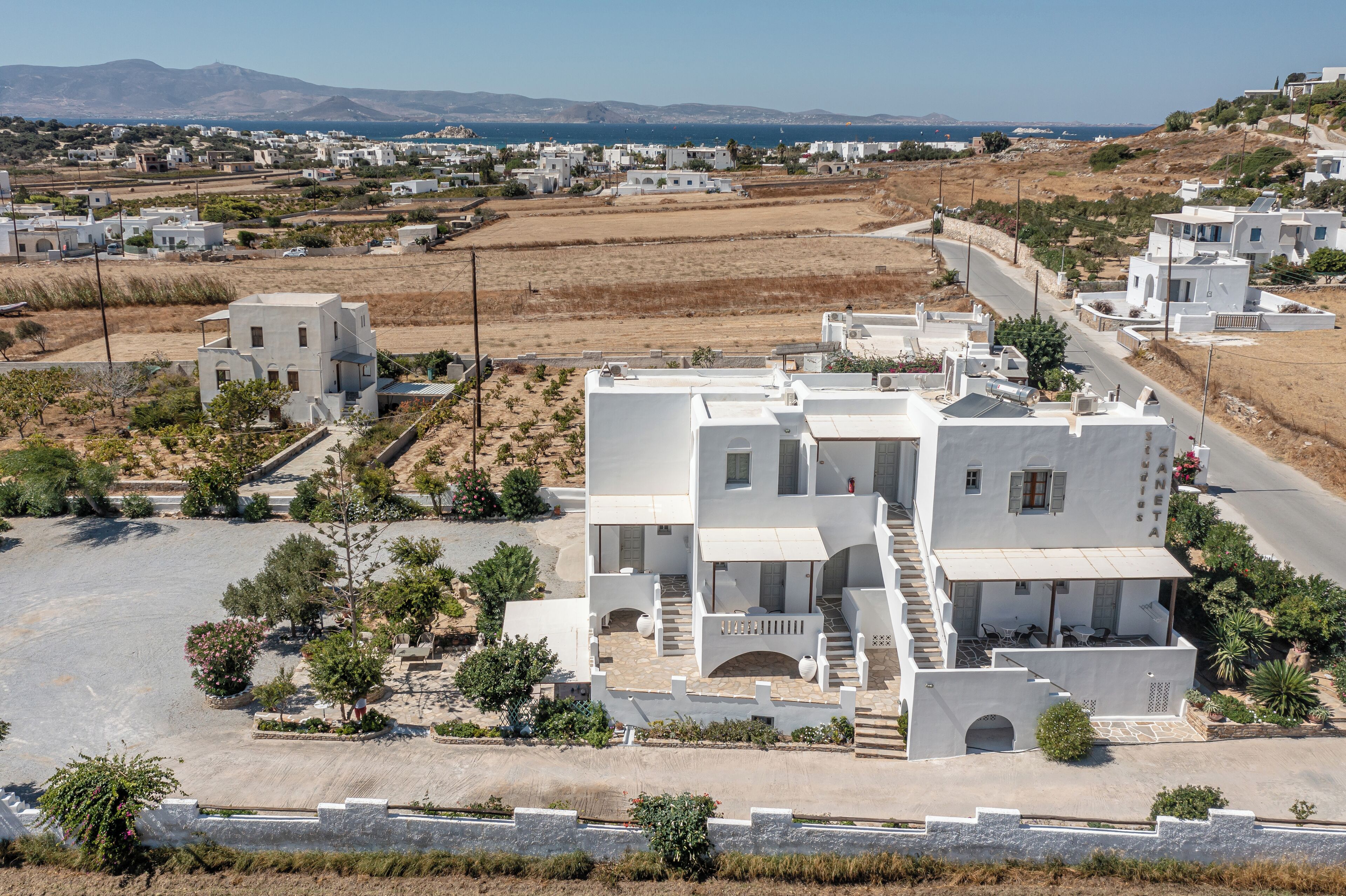 Un bâtiment blanc doté d’une cour intérieure, entouré de verdure et offrant une vue sur la mer.