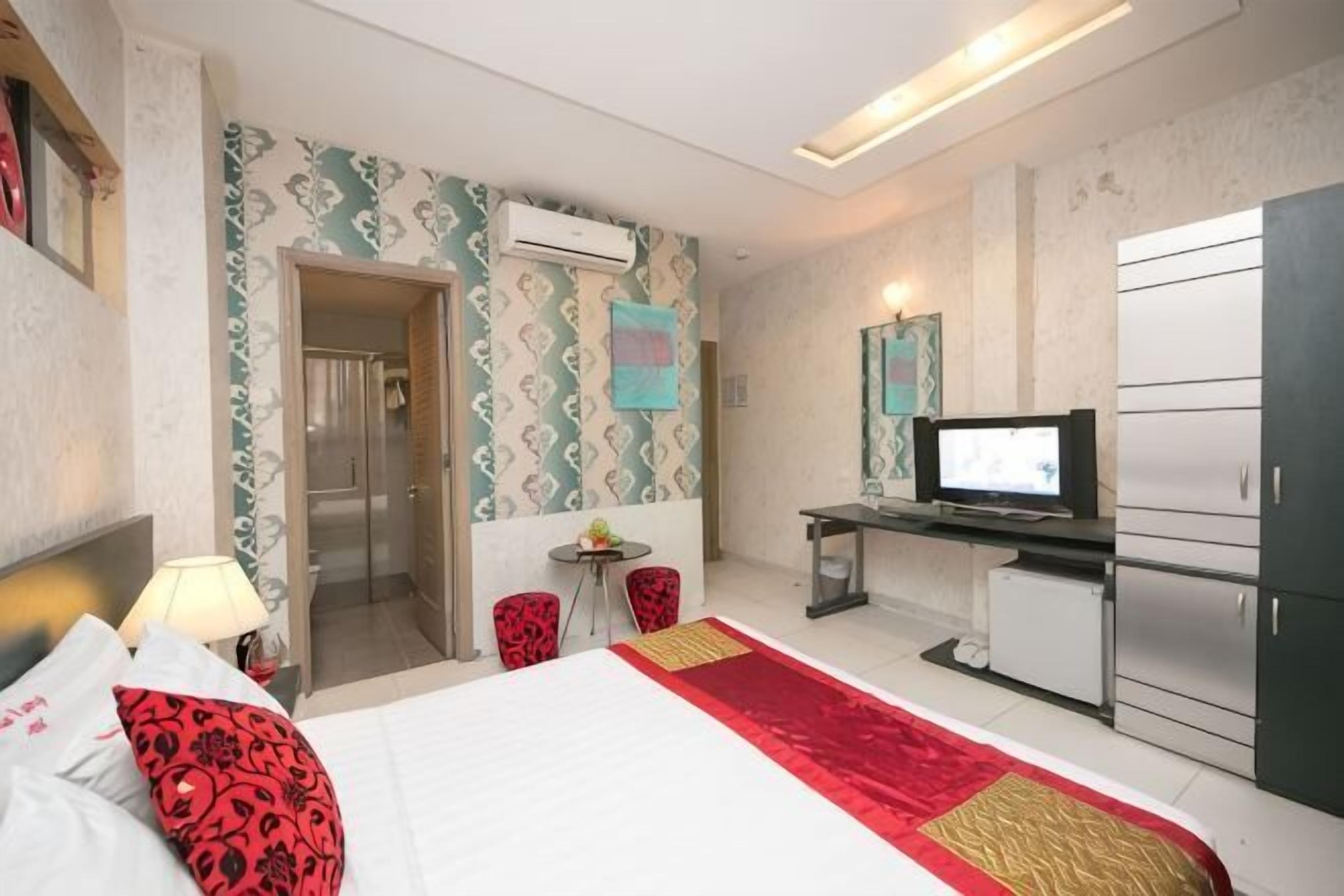 Une chambre d’hôtel comprenant un lit, un bureau avec une télévision, une petite table et une armoire.