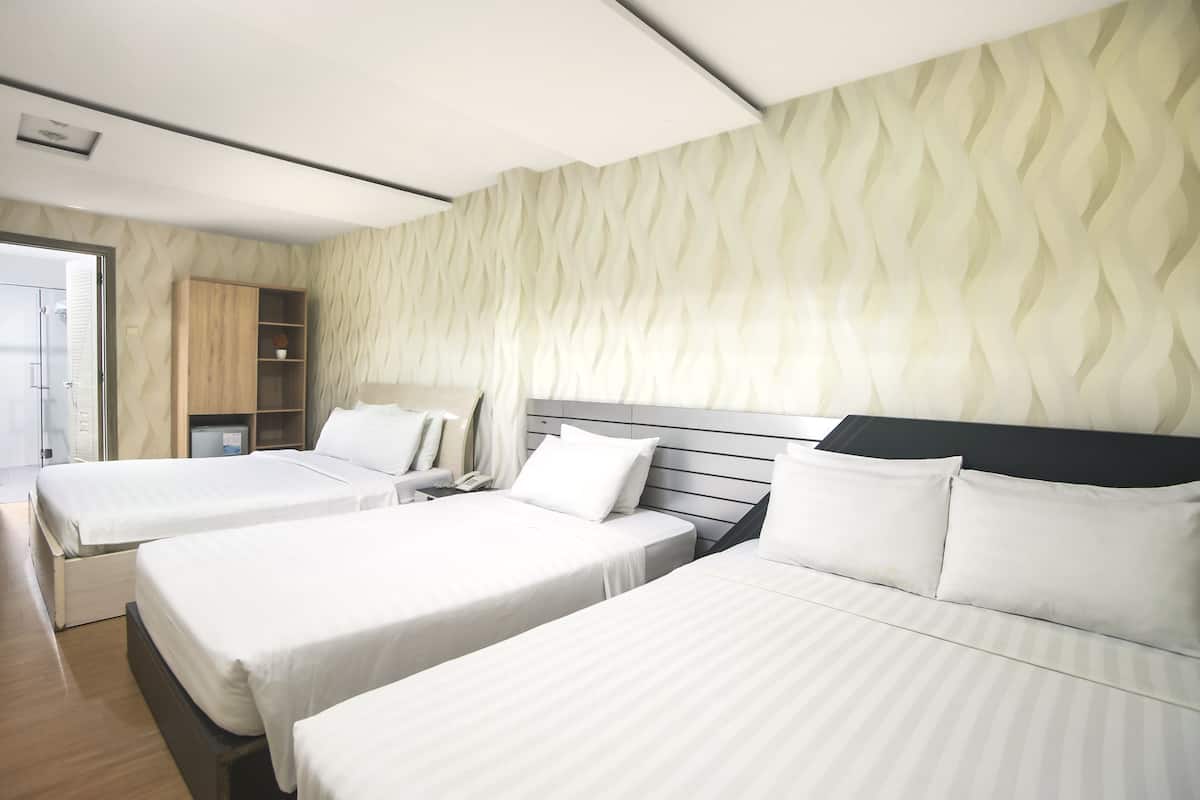 A hotel room with three beds, a wardrobe, and a wall with a wavy pattern.