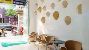A hotel lobby with a reception desk, seating area, and a wall decorated with circular patterns. - Saigon Charm Hotel (Ho Chi Minh City)