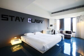 Una habitación de hotel moderna con una cama grande, un sofá, un escritorio y una pared con la inscripción 'STAY CLASSY'.